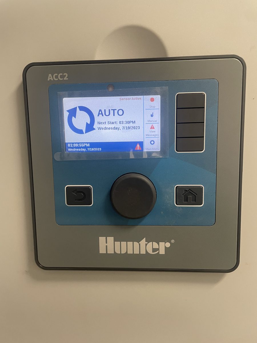 Hunter ACC2 commercial irrigation controller running in AUTO mode with an active sensor, wired to an irrigation pump start relay