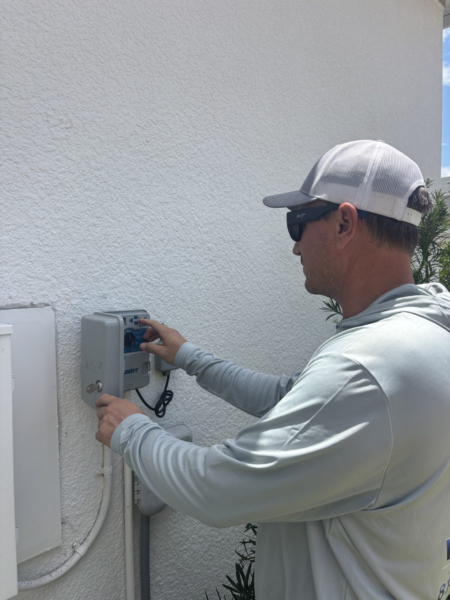 Water Oak Irrigation technician programming a Hunter irrigation controller during a pump service call at a Tampa, FL home