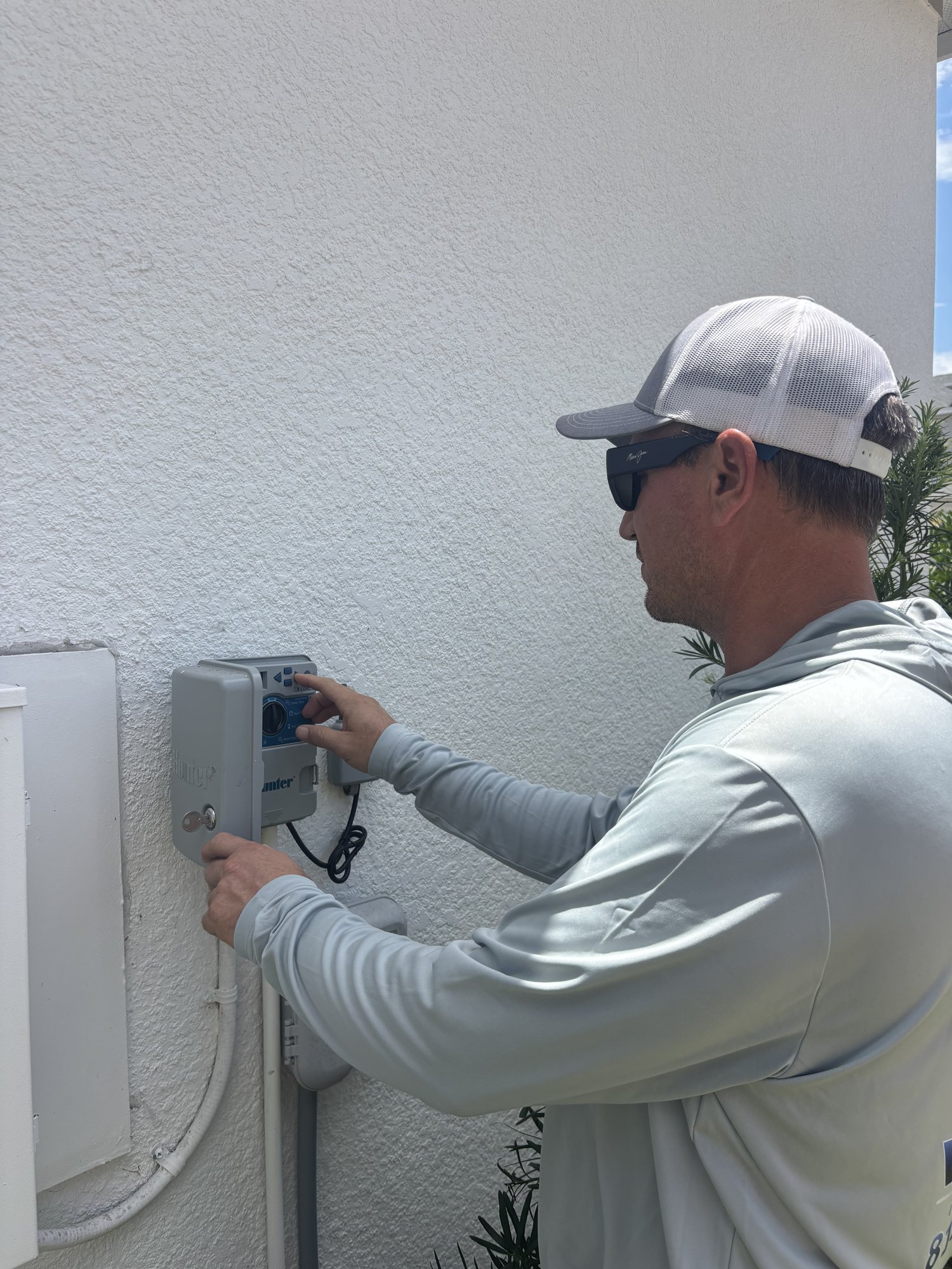 Irrigation technician programming a sprinkler system timer for watering restriction compliance in Tampa, FL